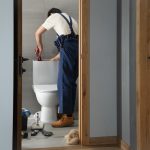 man fixing a toilet in a bathroom