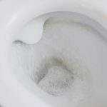 close-up of a toilet with water running in the bowl